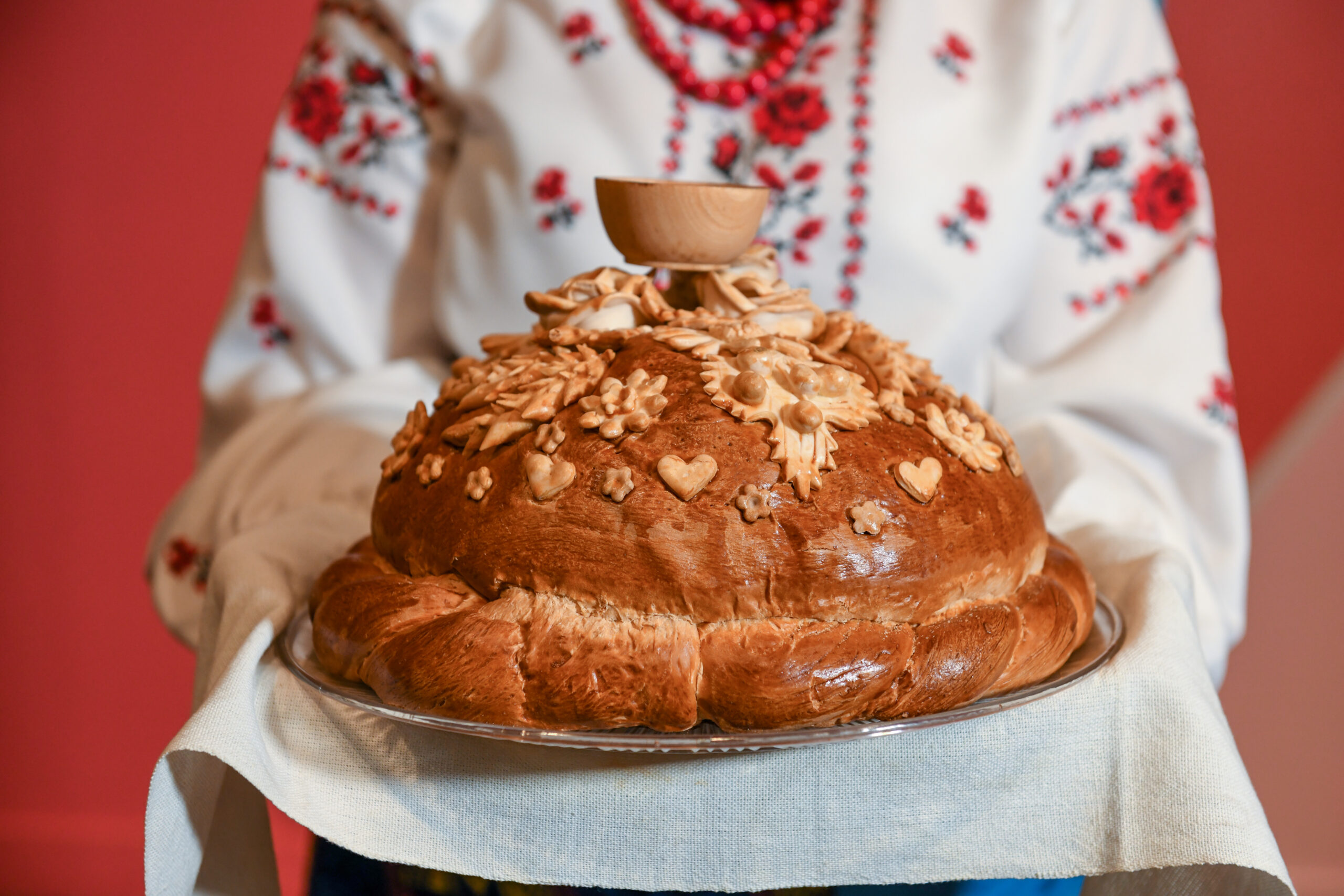 An elaborately decorated loaf of bread with designs of hearts and plants made from lighter pieces of bread.