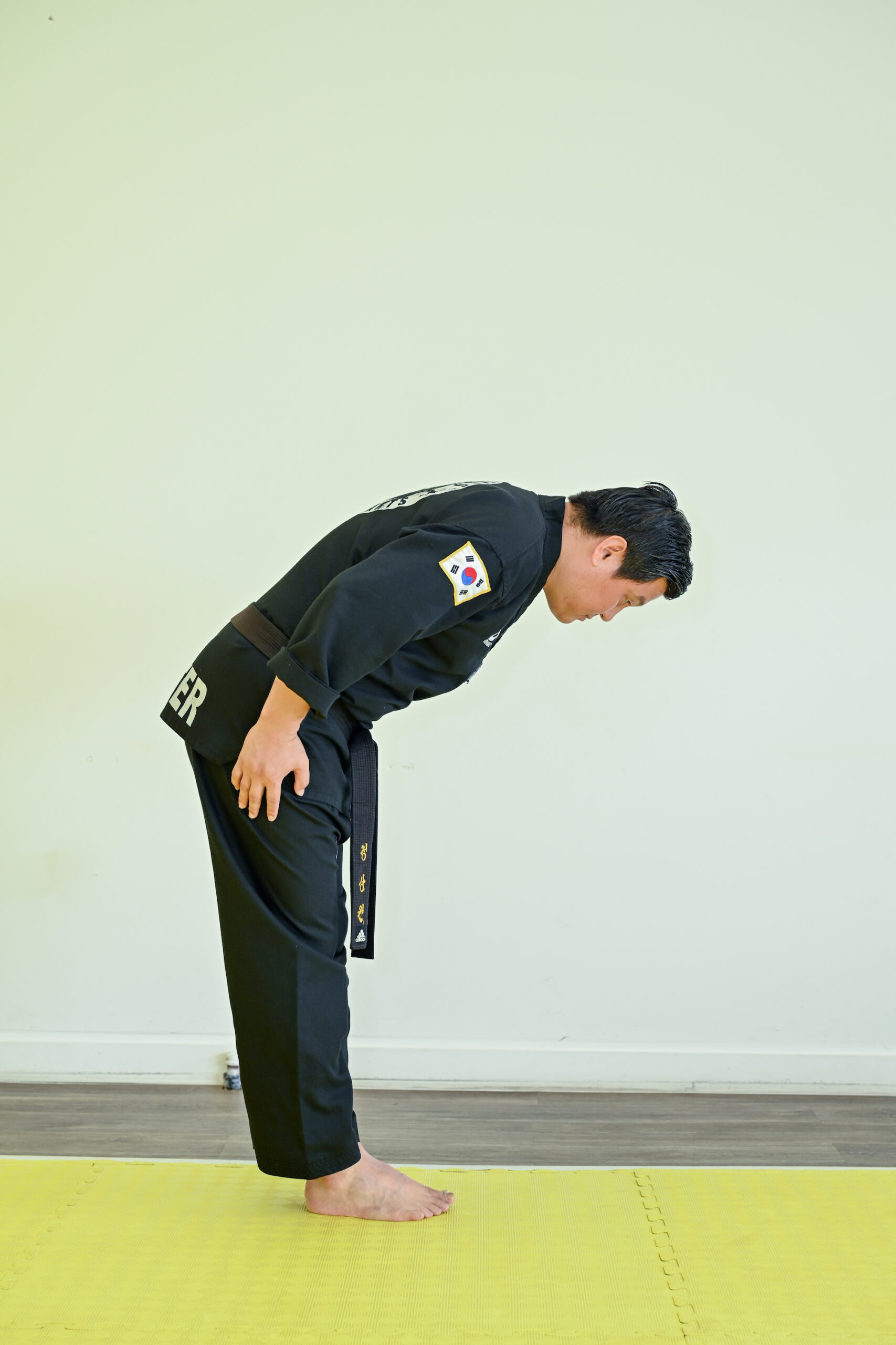 Master Jeong bows forward with his head facing the ground and his arms at his side.