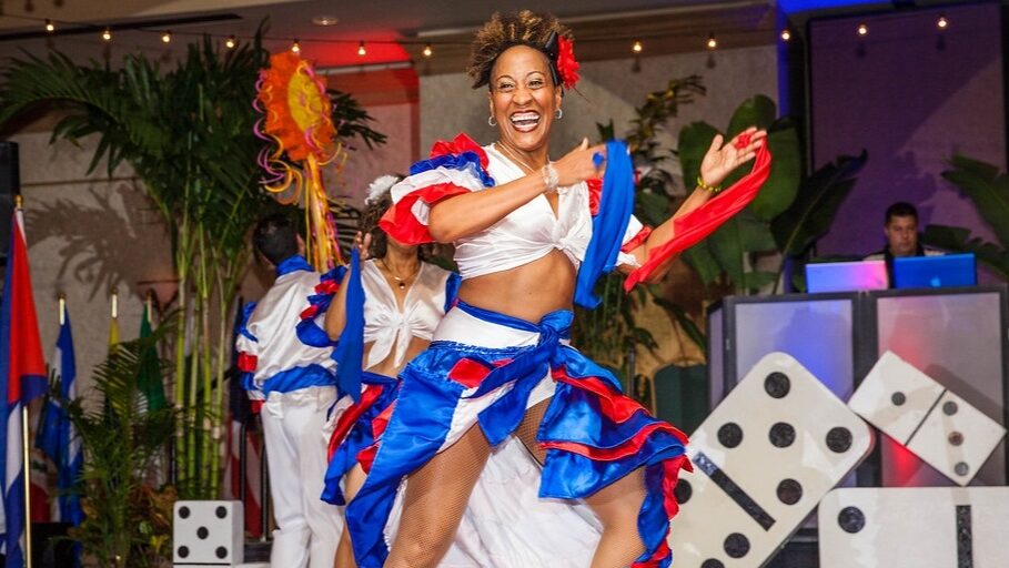 Dancer in a white red and blue top and skirt dances in front of large domino piece backdrop