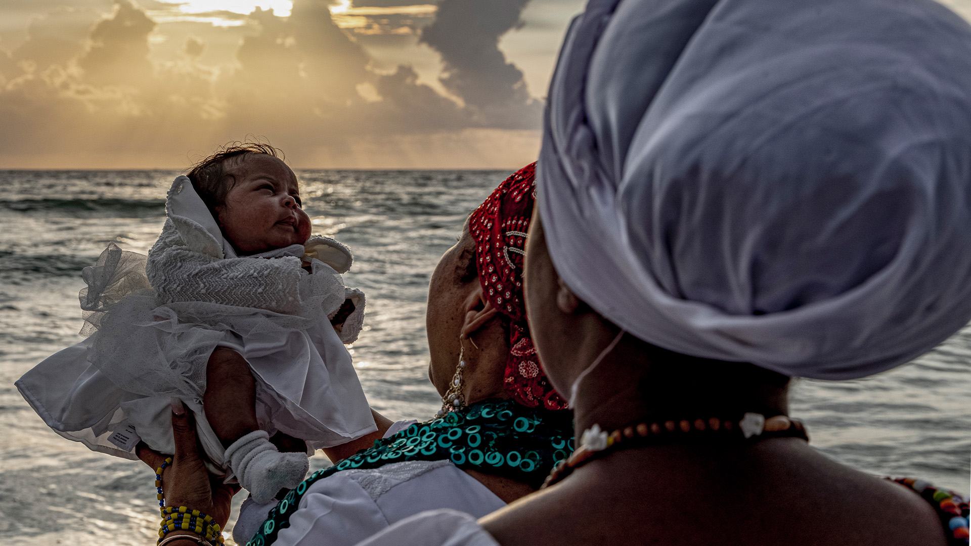 Person holding baby by ocean