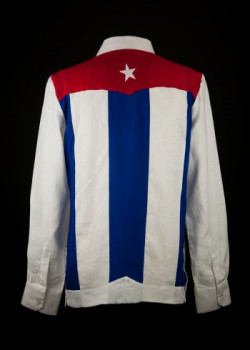 Guayabera bearing Cuban flag. 2012. Linen and cotton. Emiliano Nelson. A handful of contemporary fashion designers in Cuba are attempting to revitalize the shirt’s popularity. This custom-made shirt by Emiliano Nelson is nearly identical to one previously made by Nelson for salsa star Isaac Delgado. One popular notion concerning the design of a typical guayabera is that the shirt’s back, which features a decorative shoulder yoke and multiple stripes of pleating, may have been influenced by the design of the Cuban flag. Collection of Museum of Miami. Guayabera bearing Cuban flag. 2012. Linen and cotton. Emiliano Nelson. A handful of contemporary fashion designers in Cuba are attempting to revitalize the shirt’s popularity. This custom-made shirt by Emiliano Nelson is nearly identical to one previously made by Nelson for salsa star Isaac Delgado. One popular notion concerning the design of a typical guayabera is that the shirt’s back, which features a decorative shoulder yoke and multiple stripes of pleating, may have been influenced by the design of the Cuban flag. Collection of Museum of Miami.